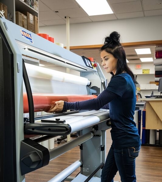 An image of a FASTSIGNS employee using an industrial grade printer.